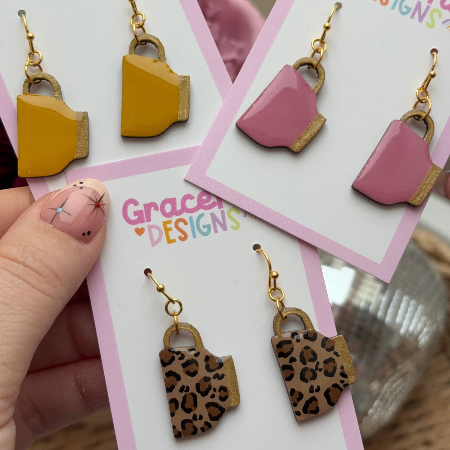 Earrings on cards with 'Graceful Designs' branding held by a hand.