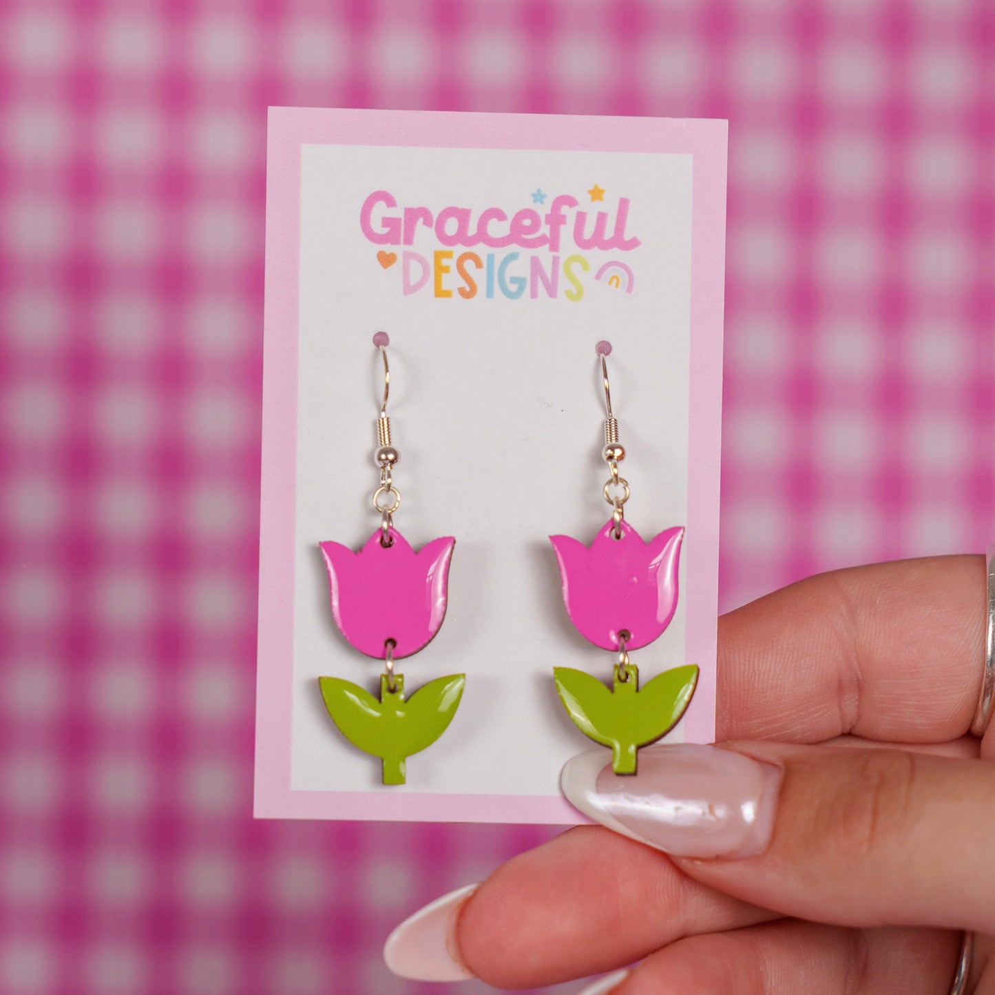 Pink and green tulip-shaped earrings on a 'Graceful Designs' card against a pink checkered background.