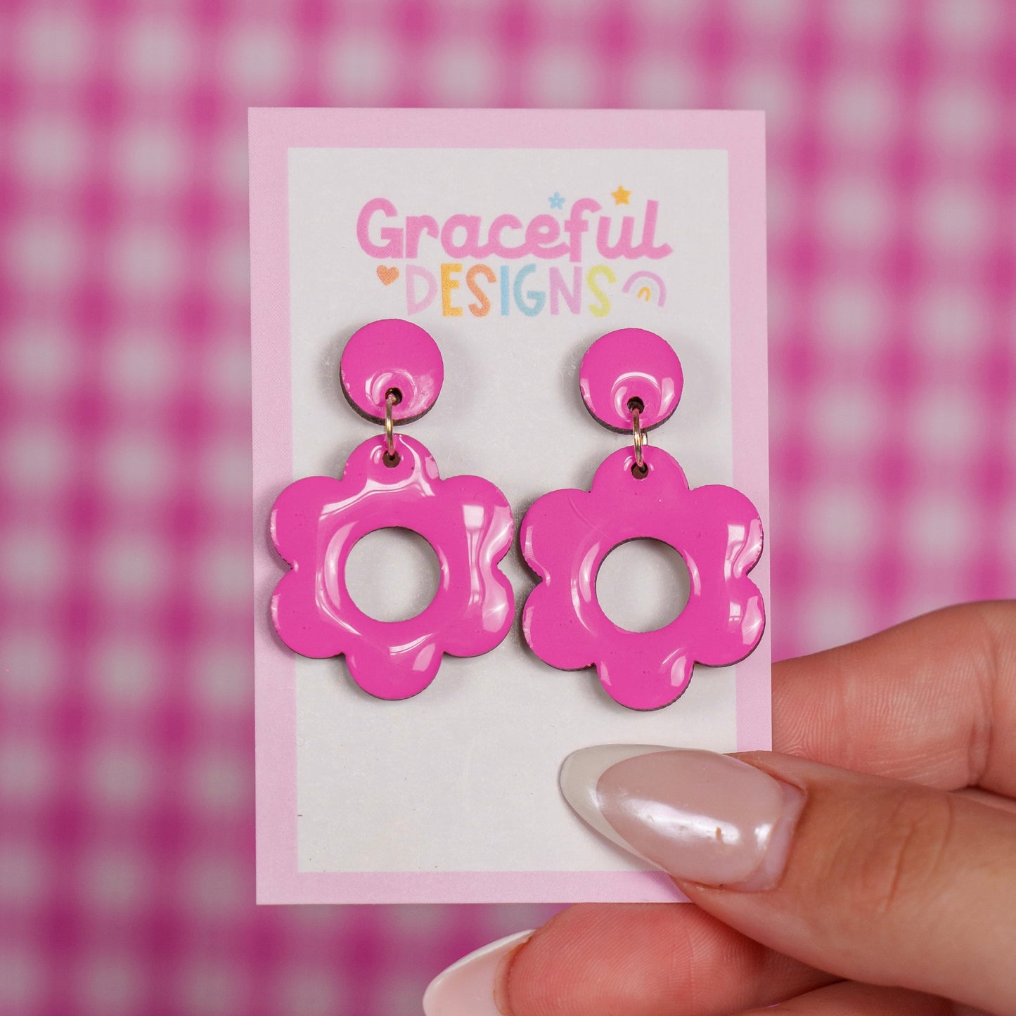 Pink floral earrings on a 'Graceful Designs' card against a pink checkered background