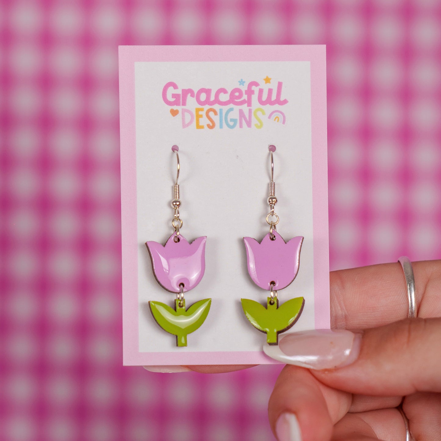 Pink and green tulip-shaped earrings on a 'Graceful Designs' card against a pink checkered background.