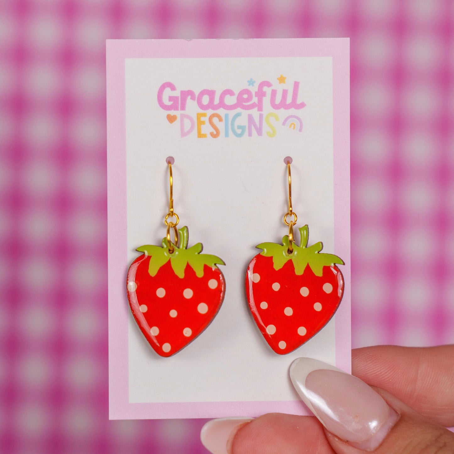 Strawberry-shaped earrings on a 'Graceful Designs' card against a pink and white checkered background.