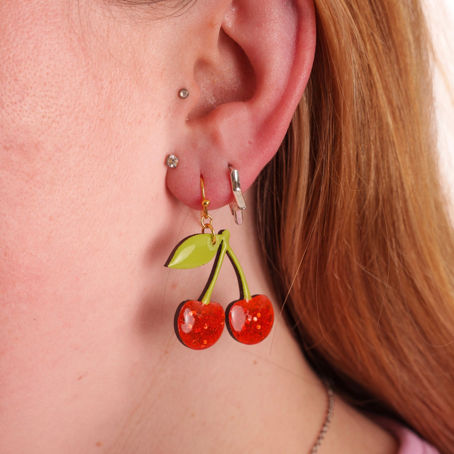 Close-up of a person wearing cherry-shaped earrings.