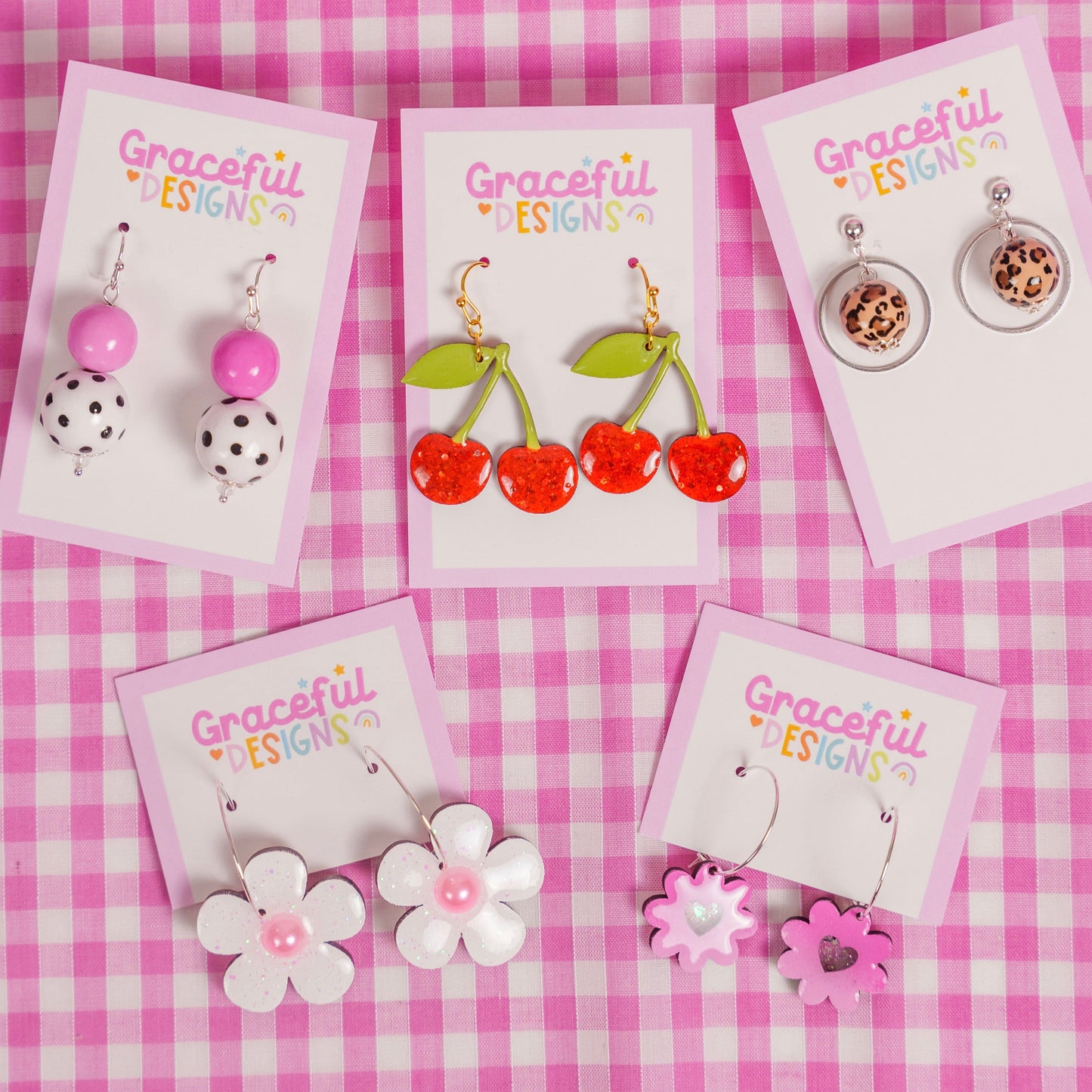 Set of earrings on cards with 'Graceful Designs' branding on a pink checkered background