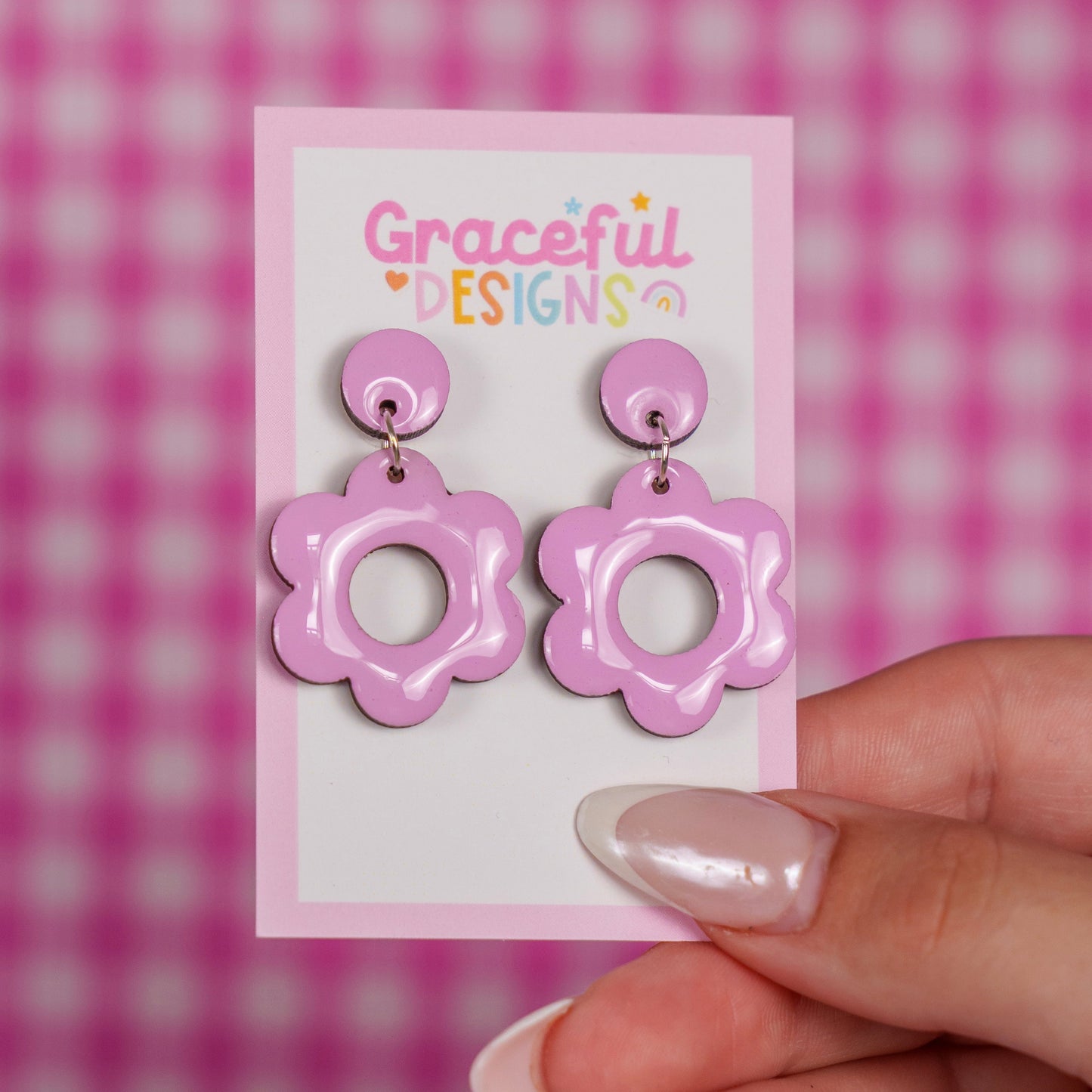 Pink floral earrings on a 'Graceful Designs' card against a pink checkered background