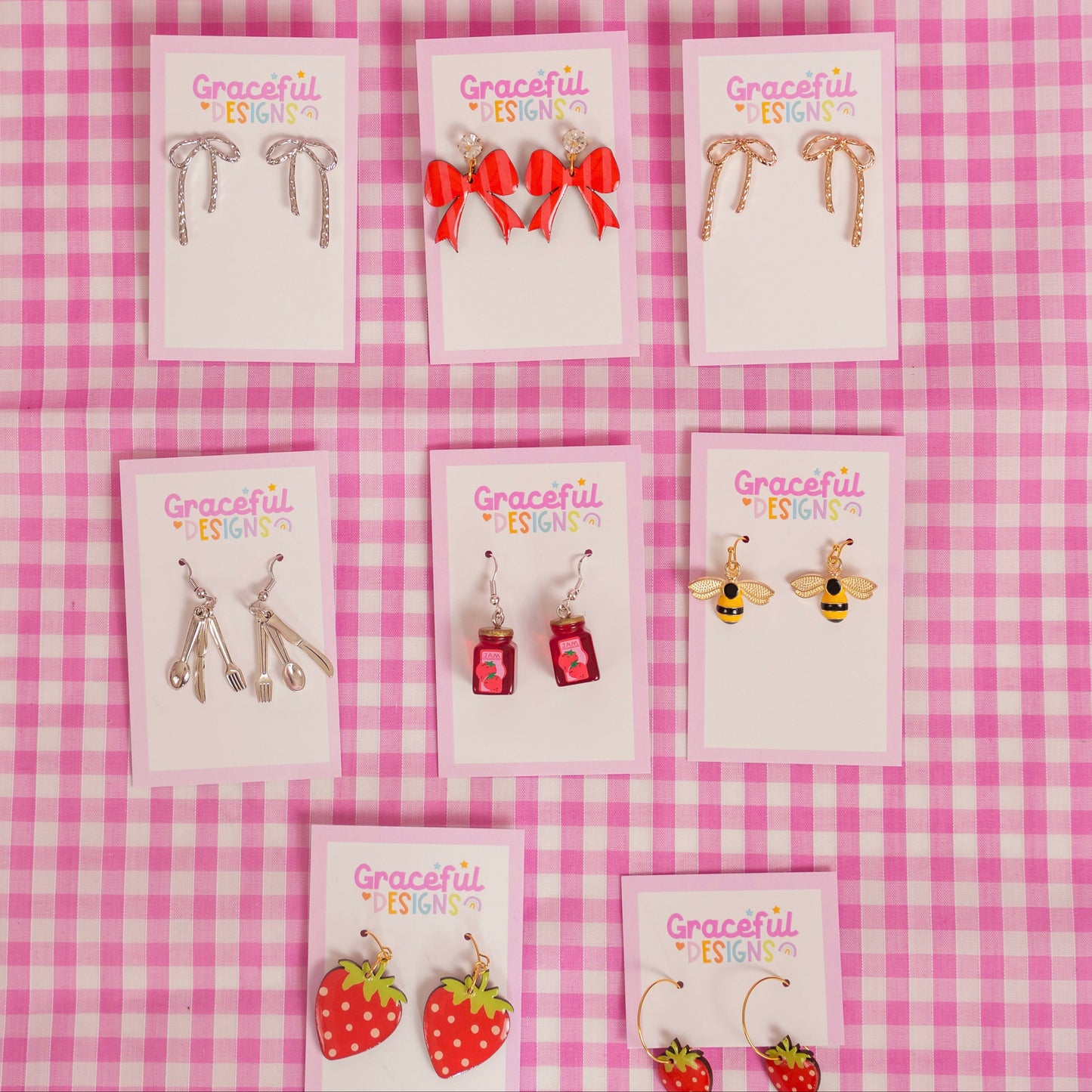 Set of earrings on display with 'Graceful' branding against a pink checkered background