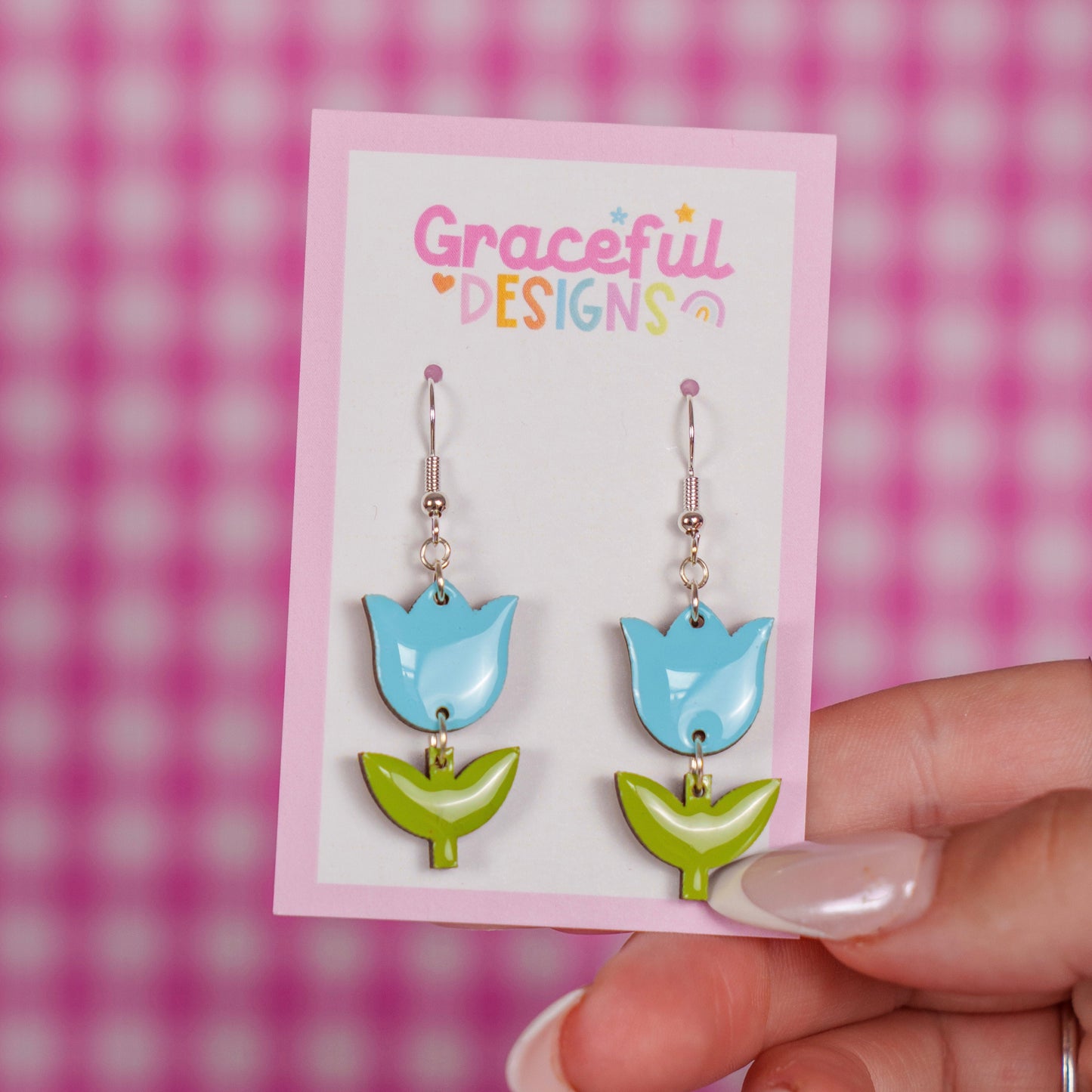 Tulip-shaped earrings on a 'Graceful Designs' card against a pink checkered background