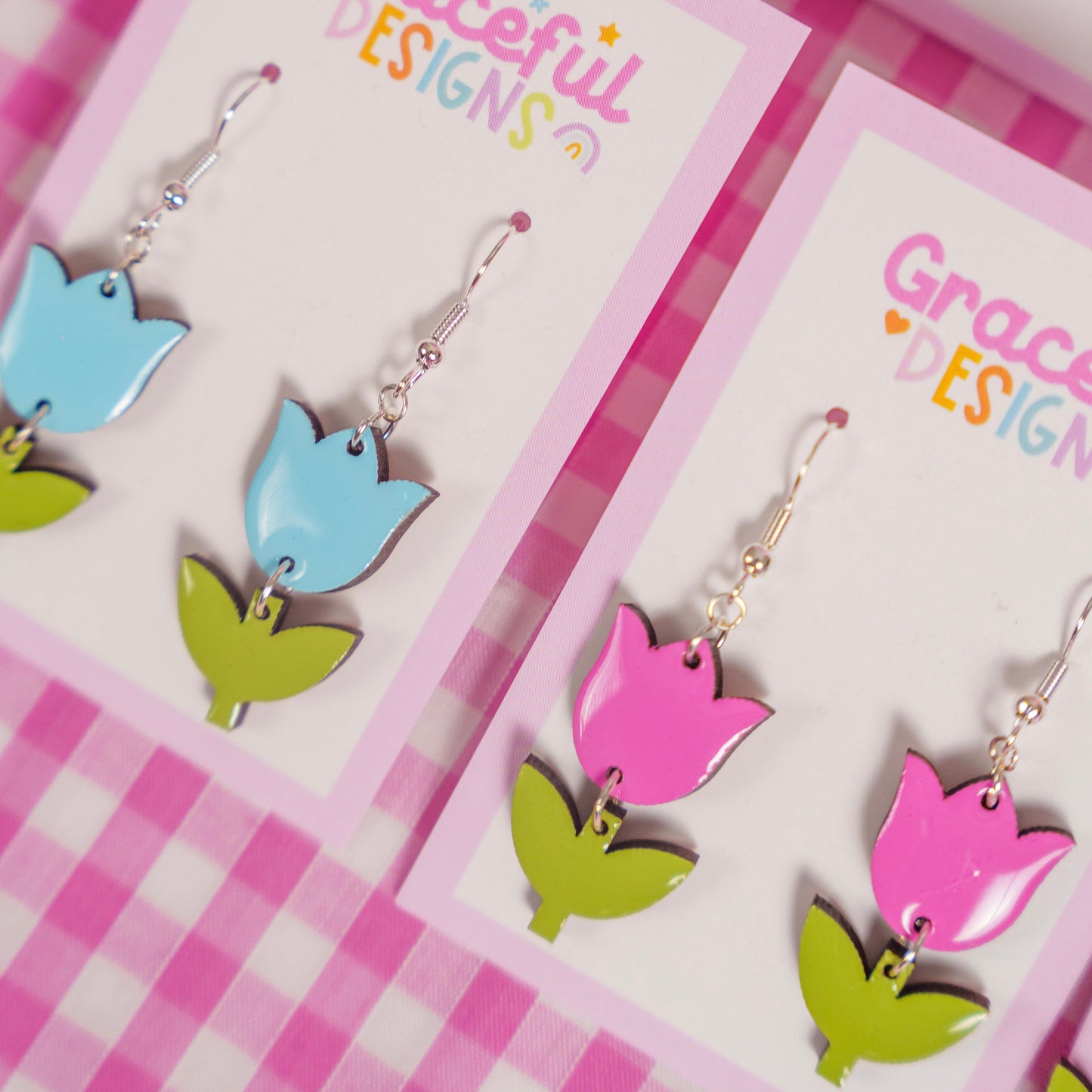 Colorful tulip-shaped earrings on 'Graceful Designs' cards with a pink checkered background.