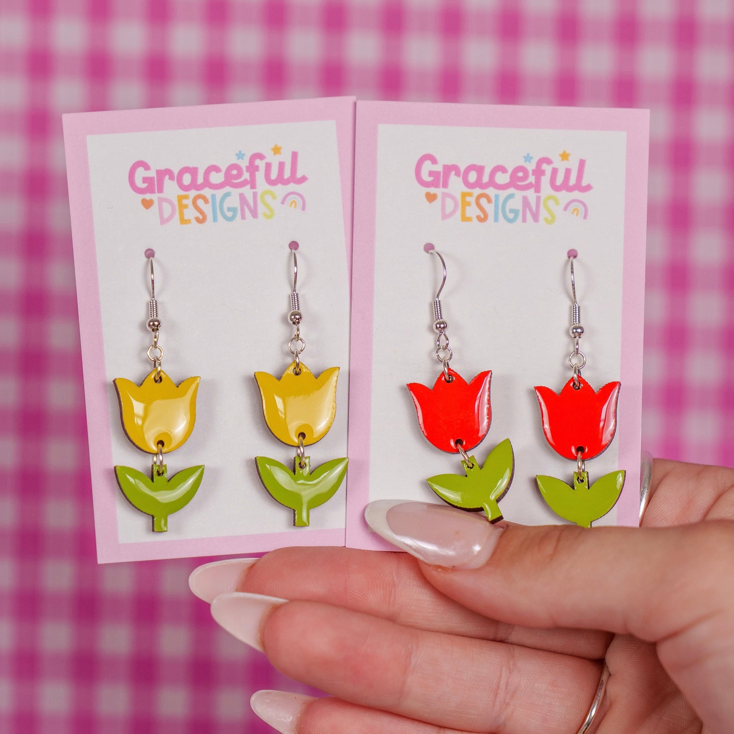 Colorful tulip-shaped earrings on a 'Graceful Designs' card against a pink checkered background.