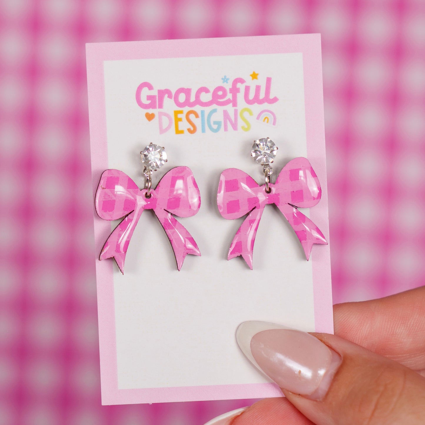 Pink bow earrings on a 'Graceful Designs' card with a pink checkered background