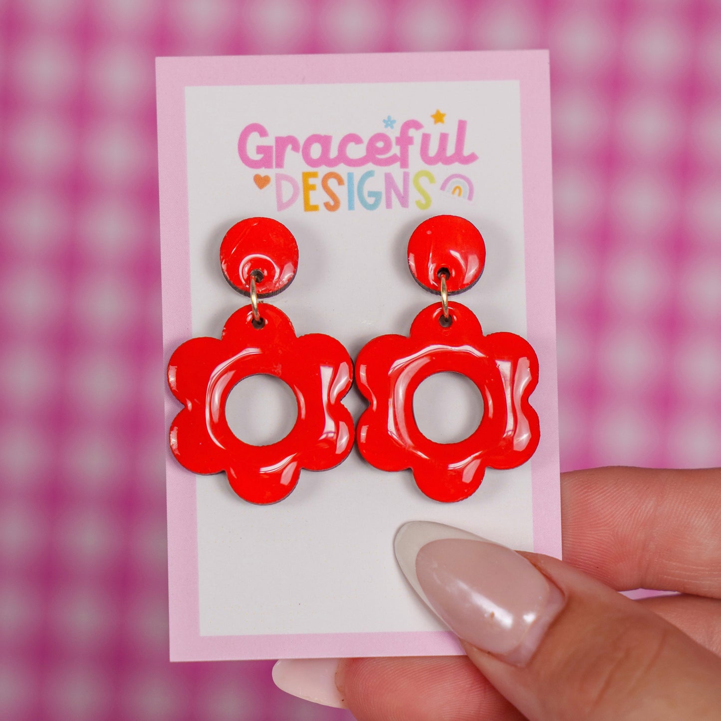 Red floral earrings on a 'Graceful Designs' card against a pink checkered background