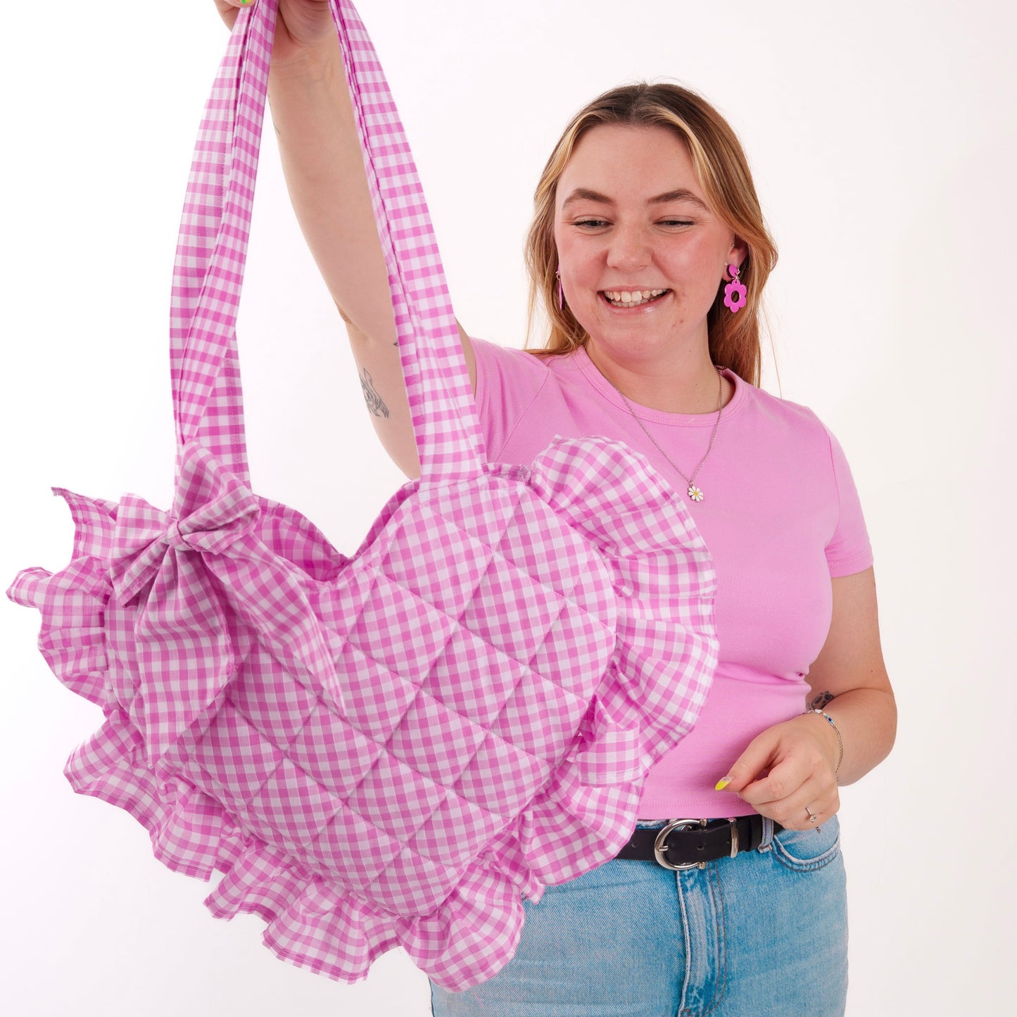 Person holding a pink gingham bag with ruffles against a white background