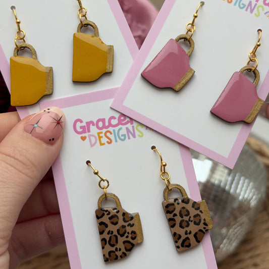 Earrings on cards with 'Graceful Designs' branding held by a hand.