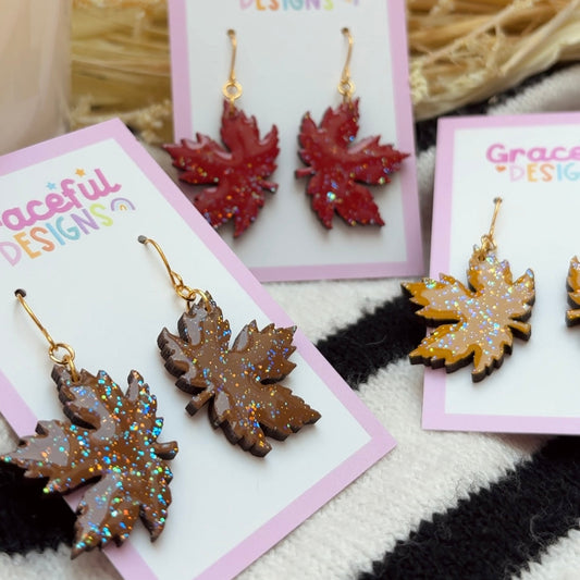 Maple leaf earrings on 'Graceful Designs' cards with a textured background