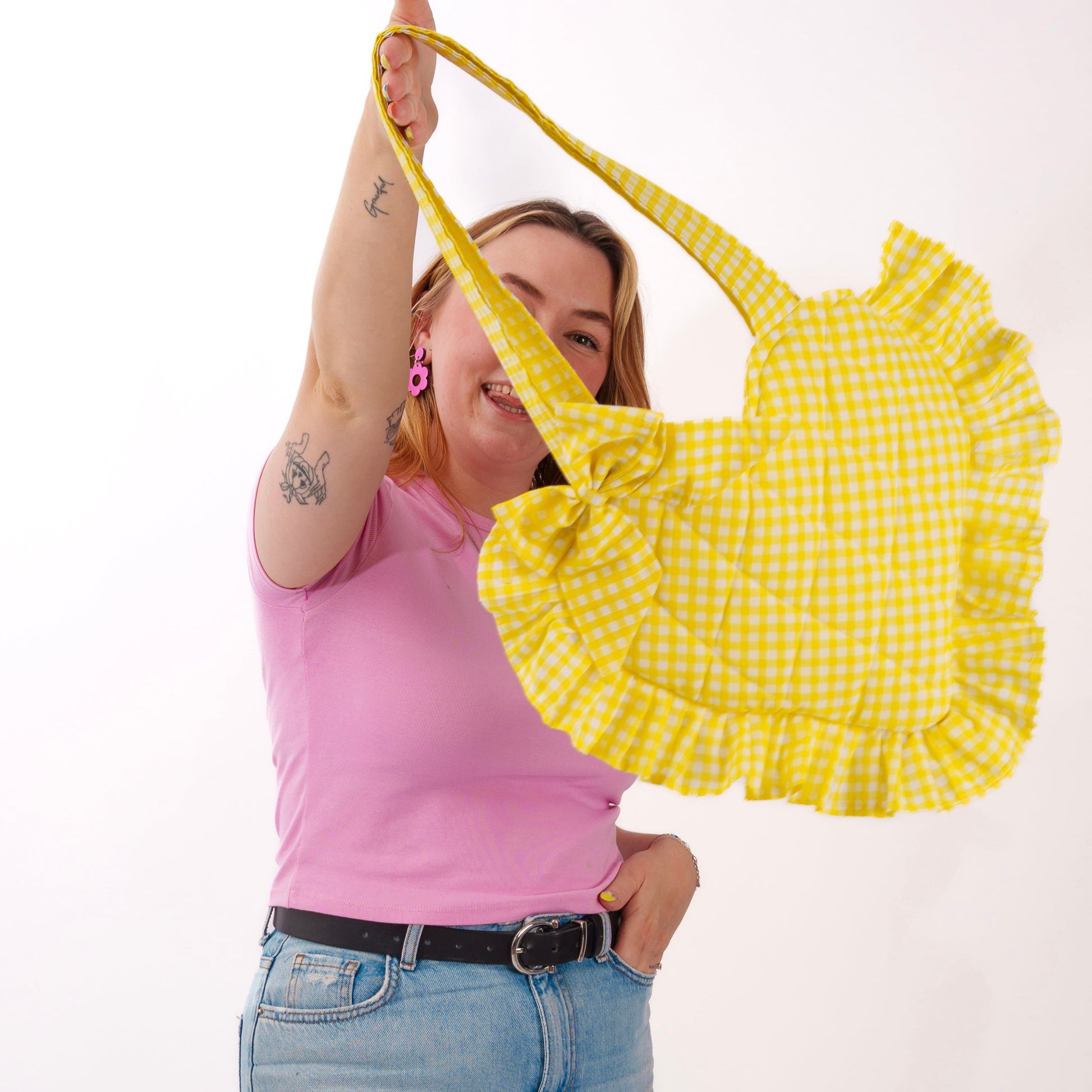Person holding a yellow checkered bag against a white background