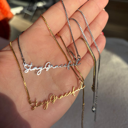 Hand holding multiple necklaces with different designs and colors.