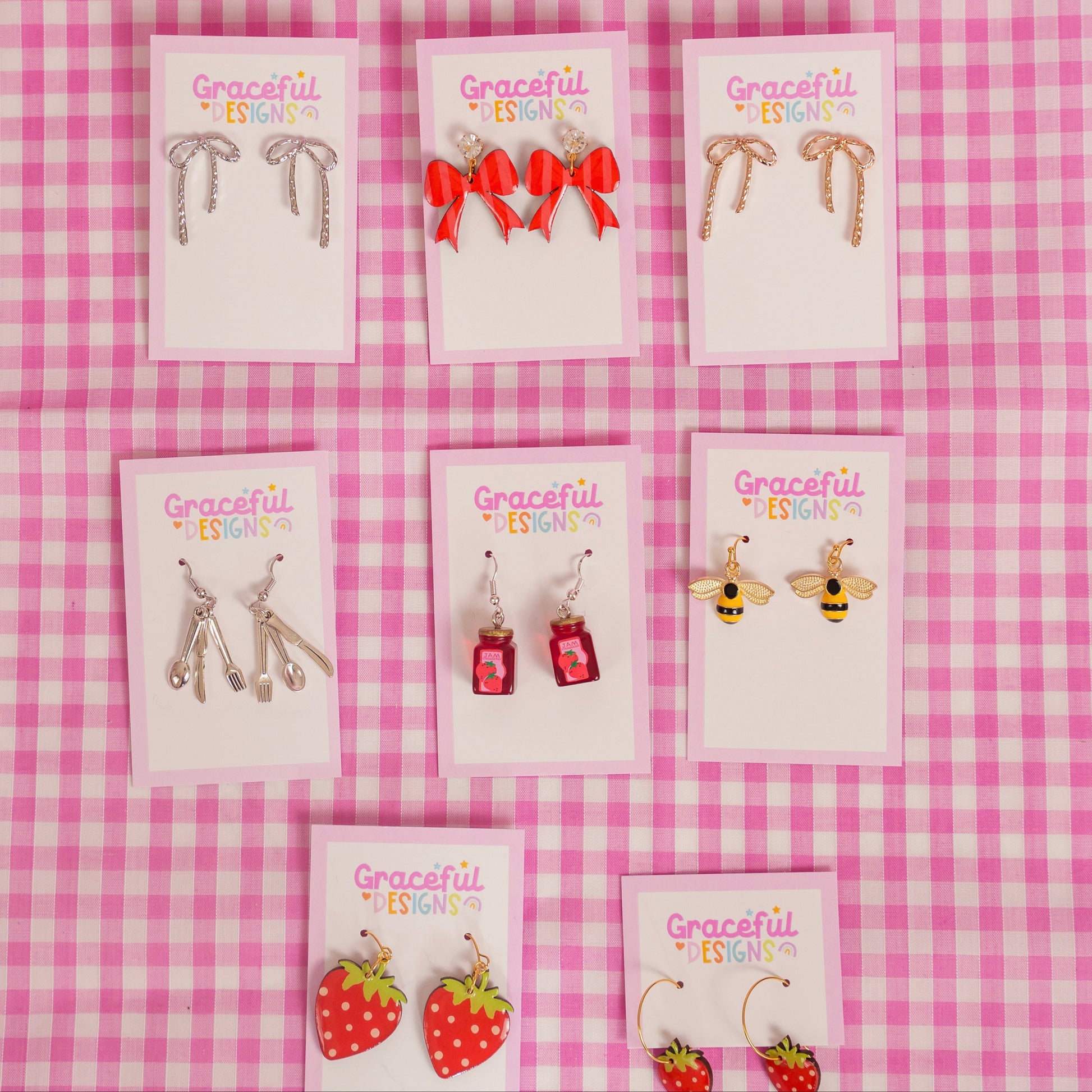 Set of earrings on display with 'Graceful' branding against a pink checkered background