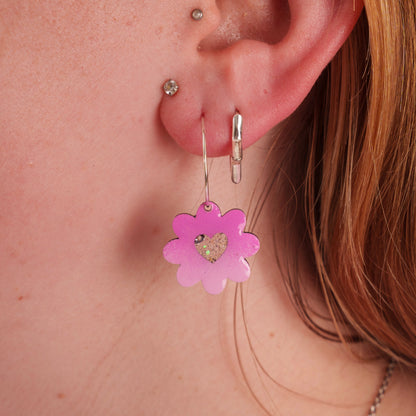 Close-up of an ear wearing a pink flower-shaped earring.
