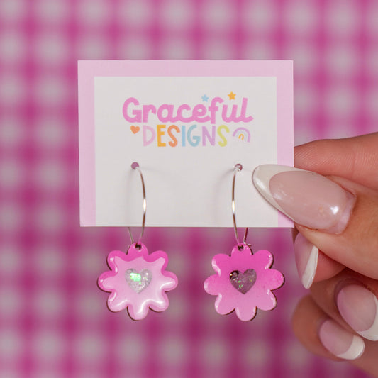 Pink flower-shaped earrings on a 'Graceful Designs' card against a pink checkered background.
