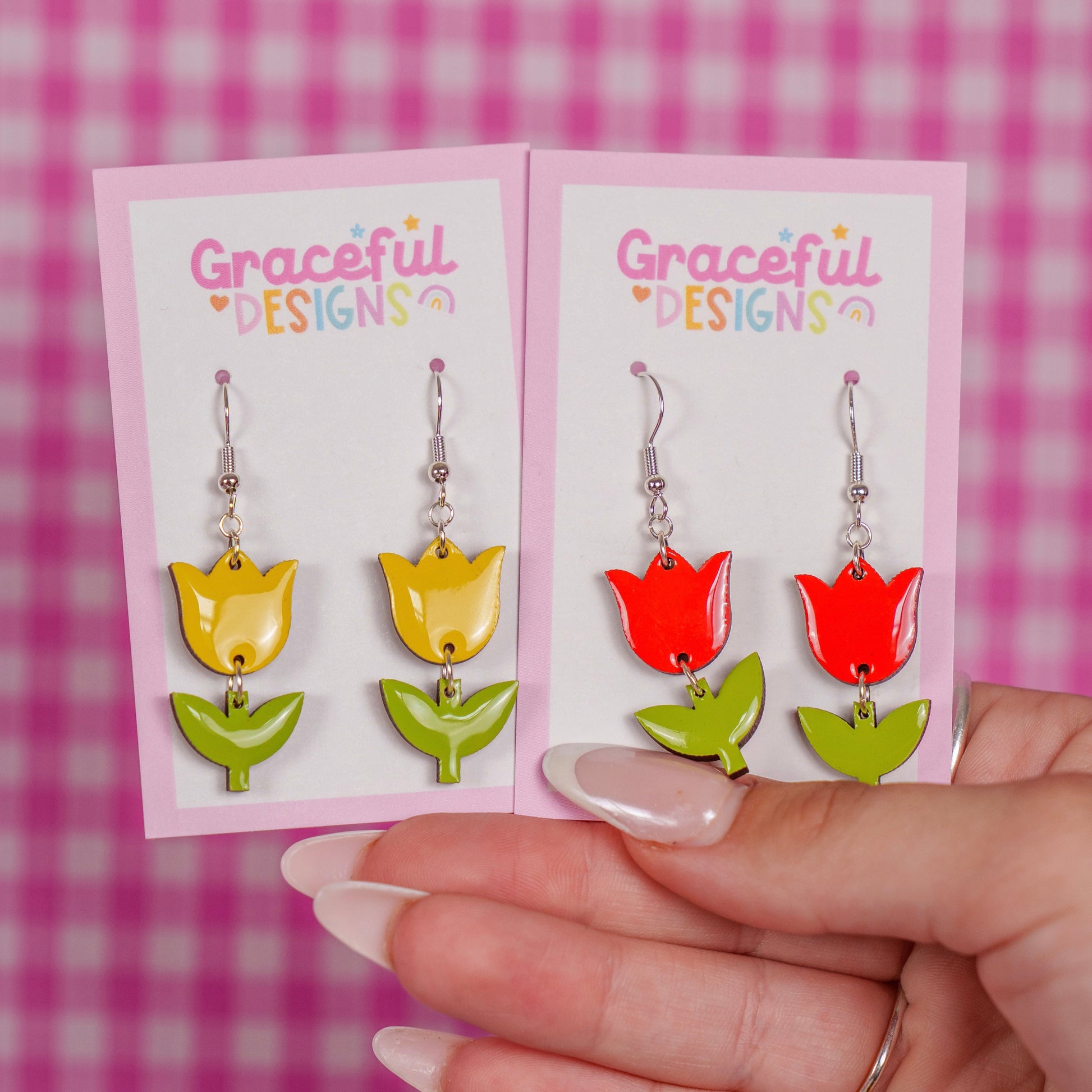 Colorful tulip-shaped earrings on a 'Graceful Designs' card against a pink checkered background.