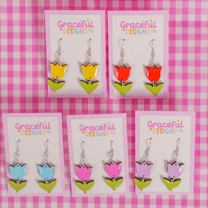 Set of colorful tulip-shaped earrings on 'Graceful Designs' cards against a pink checkered background.