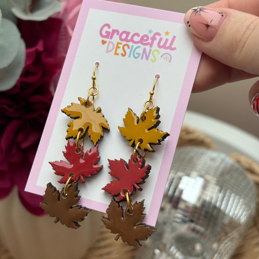 Colorful leaf-shaped earrings on a 'Graceful Designs' card with a blurred background