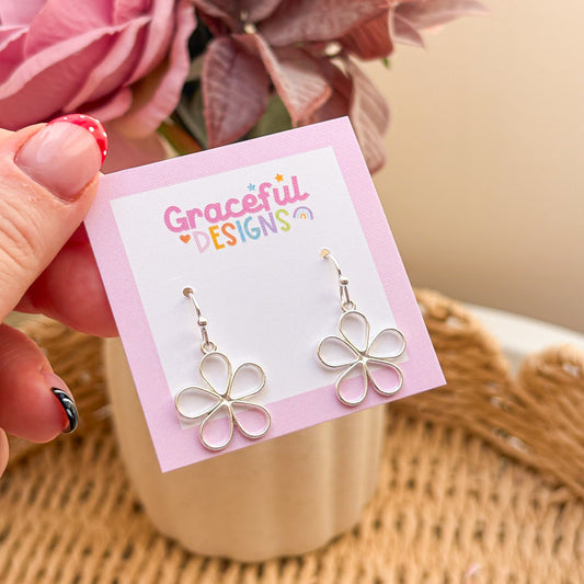 Flower-shaped earrings on a 'Graceful Designs' card with pink flowers in the background