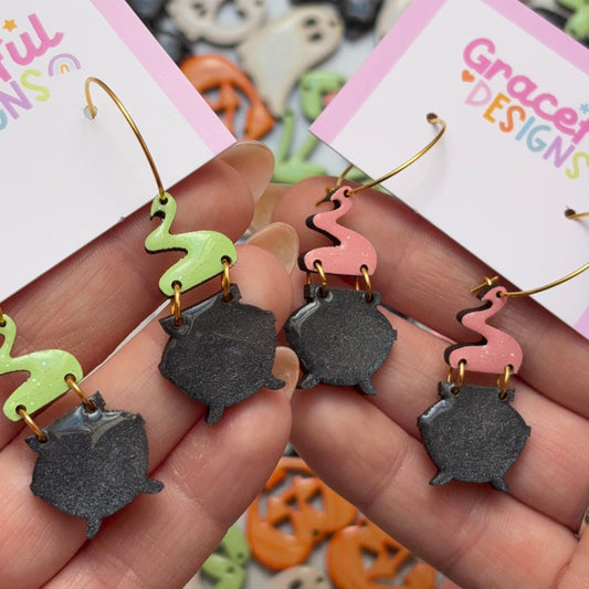 Halloween-themed earrings held in hand with 'Grace Designs' cards in the background