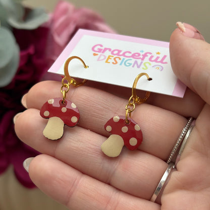 Hand holding a pair of red and gold earrings with a 'Graceful Designs' card in the background.