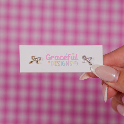 Earrings on a card with 'Graceful Designs' text against a pink checkered background