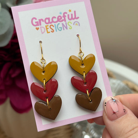 Heart-shaped earrings on a 'Graceful Designs' card held by a hand.