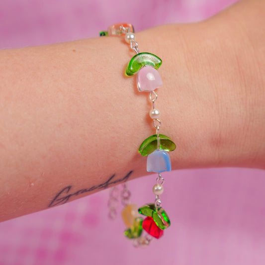 Colorful beaded bracelet on a wrist with a pink background