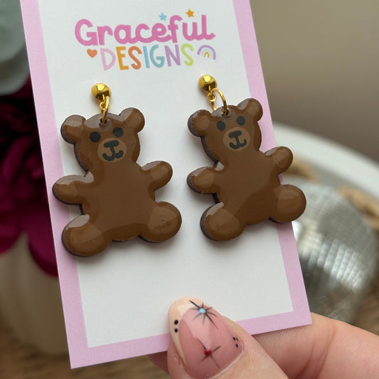 Brown bear-shaped earrings on a 'Graceful Designs' card held by a hand.