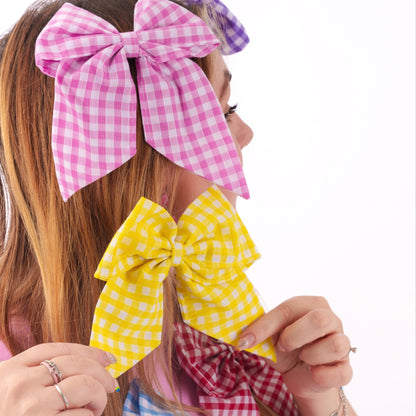 Woman holding colorful checkered hair bows against a white background