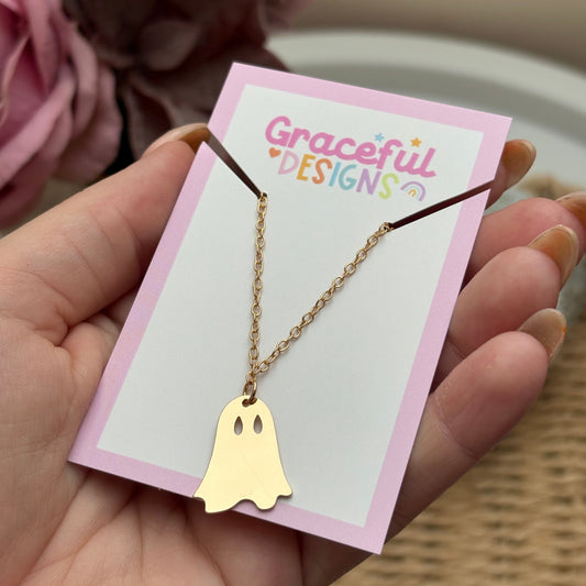 Gold necklace with a heart-shaped pendant on a 'Graceful Designs' card held by a hand.