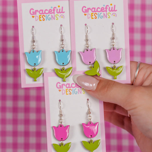 Colorful tulip-shaped earrings on 'Graceful Designs' cards against a pink checkered background.