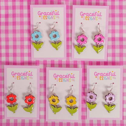 Set of colorful flower-shaped earrings on display cards with 'Graceful Designs' branding against a pink checkered background.