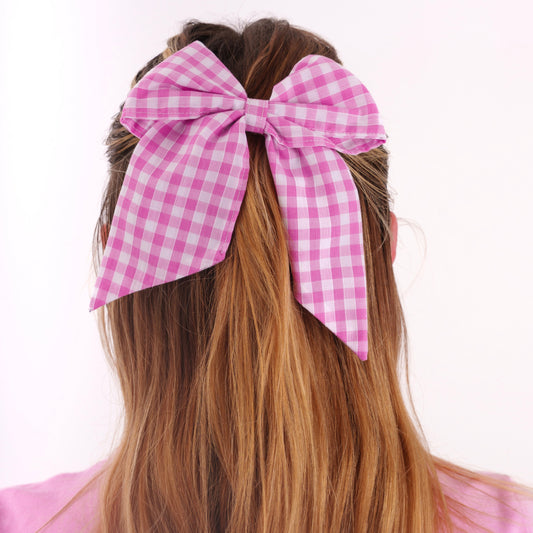Pink gingham bow in a person's hair on a white background