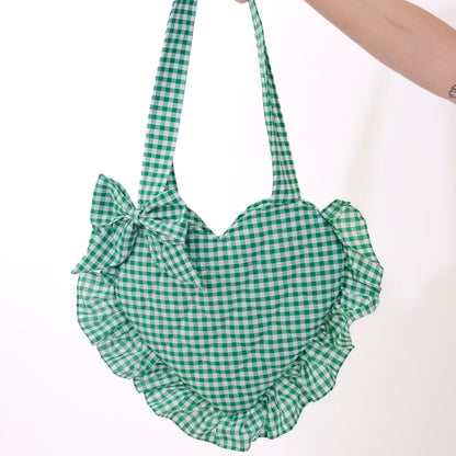 Green checkered bag with ruffles held by a hand on a white background
