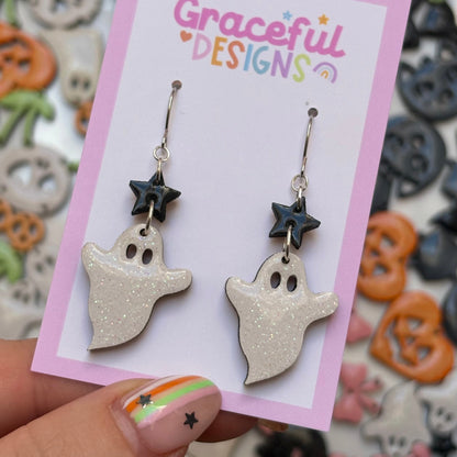 Ghost-shaped earrings on a 'Graceful Designs' card with Halloween-themed background
