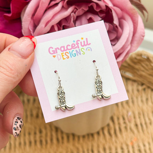 Cowboy boot earrings on a 'Graceful Designs' card with pink flowers in the background